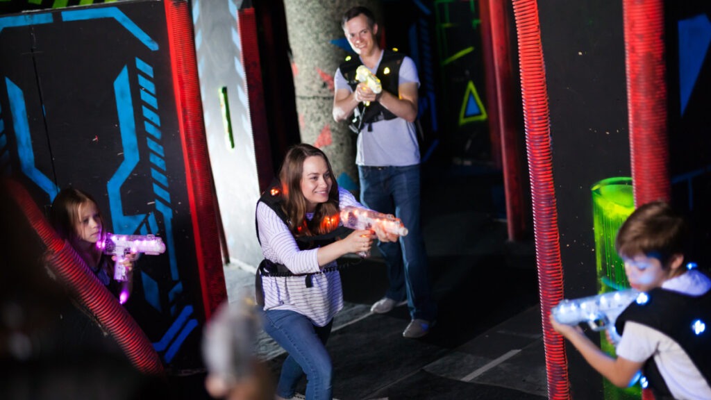 Familia jugando al laser tag o laser combat en un espacio indoor de laser game 